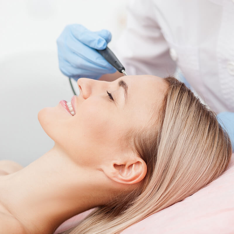 woman receiving facial treatment from a doctor's gloved hand