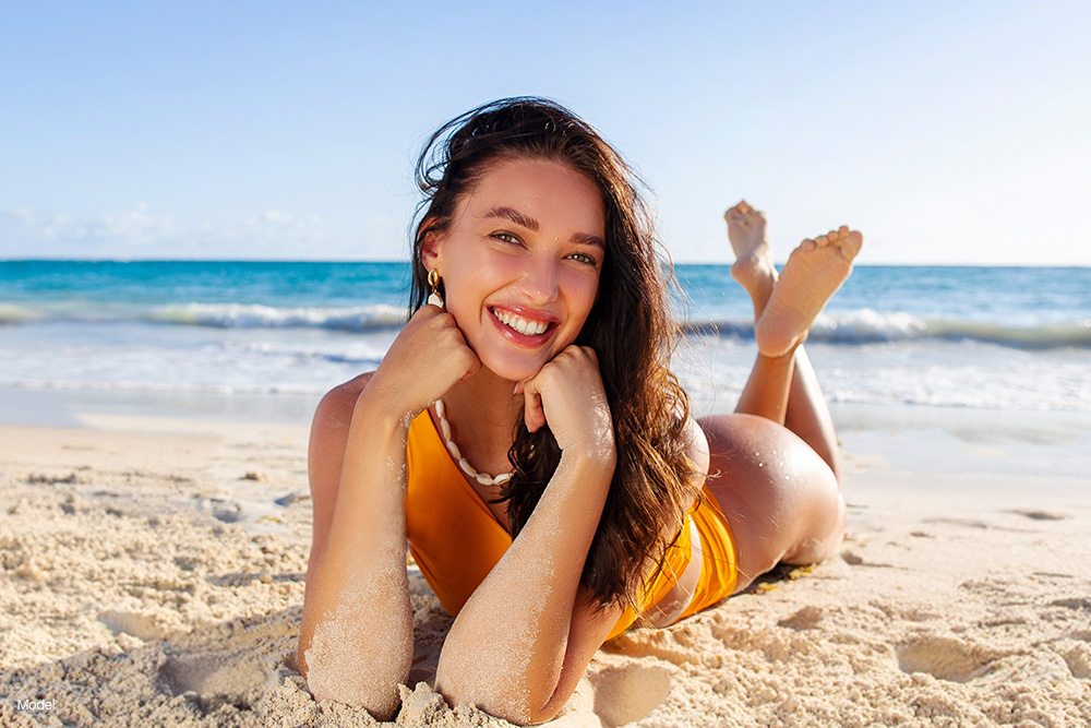 Young woman laying in the sand at the beach