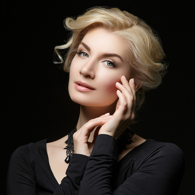 Mature woman with blonde hair touching her face